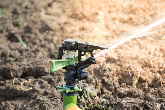 Closeup of sprinkler on the field. Water is sprayed on the field.