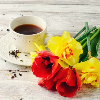 Cup of tea on saucer and a bunch of tulips