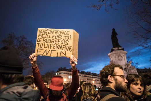 FRANCE, Paris: A man holds a sign which reads In a better world, you, the bourgeois, you will shut it at last as hundreds take part in the 14th Nuit Debout (Up All Night) movement on the Place de la Republique in Paris on April 13, 2016. The Nuit Debout or Up All Night protests began in opposition to the Socialist government's labour reforms seen as threatening workers' rights, but have since gathered a number of causes, from migrants' rights to anti-globalisation.