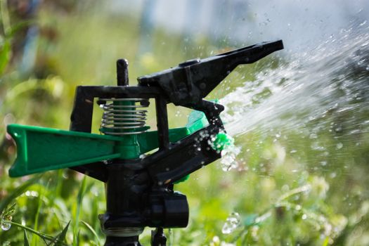 Closeup of sprinkler on the field. Water is sprayed on the field.