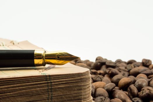 Notebook and fountain pen on coffee beans with white background