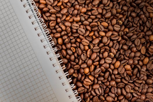 Full frame of coffee beans also with empty notebook