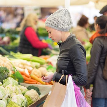 Woman buying fruits and vegetables at local food market. Market stall with variety of organic vegetable.