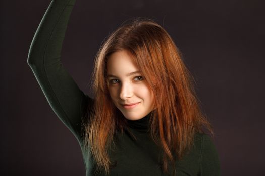 Closeup portrait of redhead woman with hand up on dark background