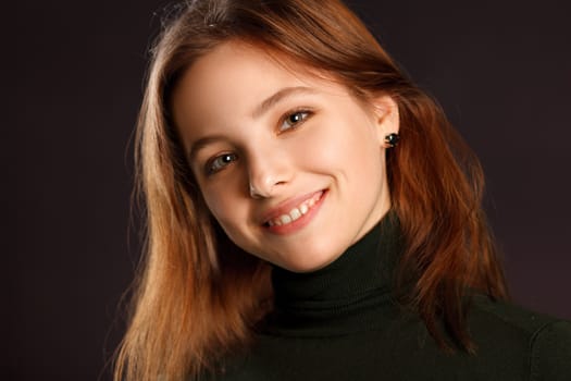 Closeup headshot portrait of redhead woman on dark background