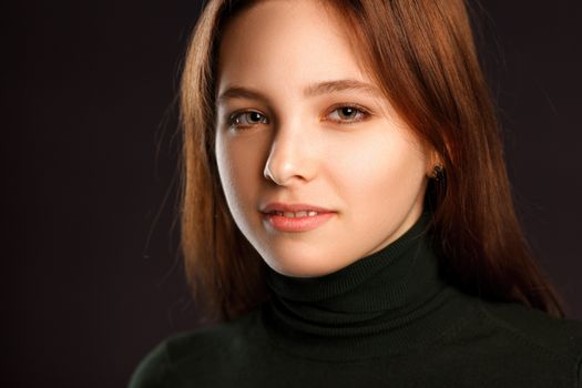 Closeup headshot portrait of redhead woman on dark background