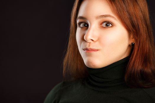 Portrait of surprised redhead woman on dark background