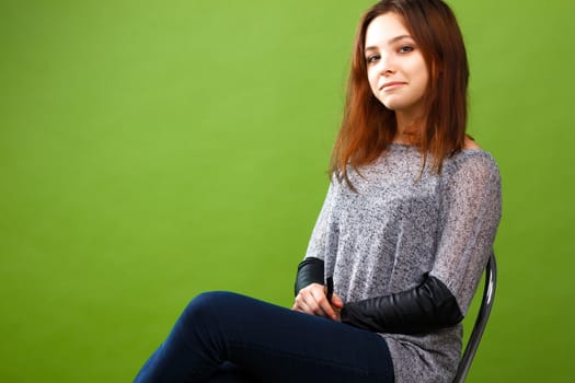 Portrait of sitting teenage girl on green background
