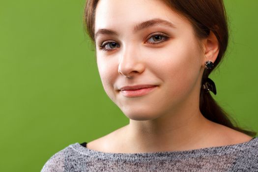 Portrait of young smiling girl on green