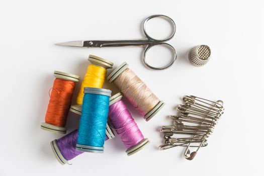 Sewing background. Accessories for needlework on wooden background. Spools of thread, scissors, sewing supplies. Set for needlework on white. Top view with copy space.