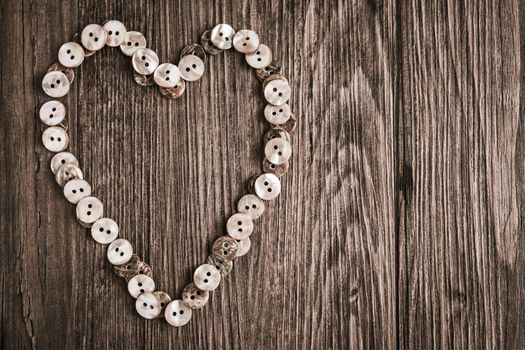 Valentine heart buttons textiles over rustic wooden texture. Top view with copy space.