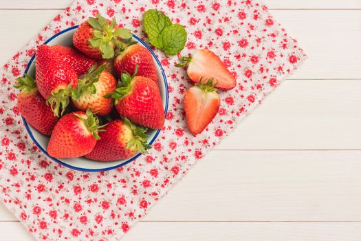 Fresh strawberries in bowl on wooden table. Top view with copy space