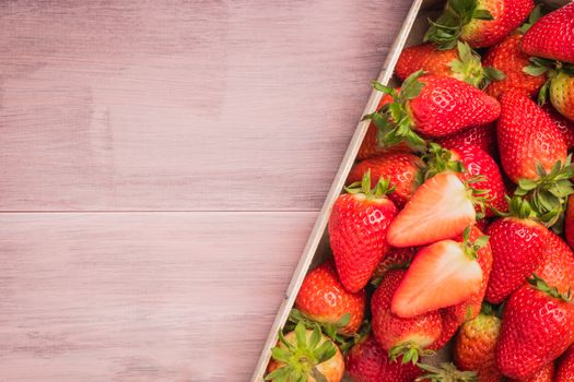 Fresh strawberries in wooden basket on wooden table. Top view with copy space