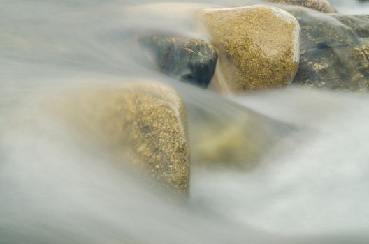 Current between the stones of the river, blurred by a slow shutter speed