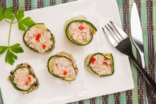 Grilled zucchini rolls with curd cheese and tuna on plate. Top view with copy space