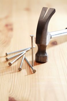 Nails set near hammer on nice wooden background