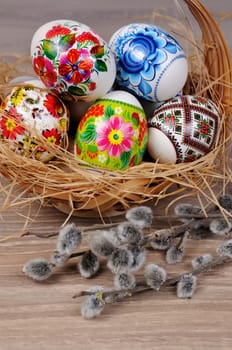 A variety of painted Easter eggs in a basket with willow branches
