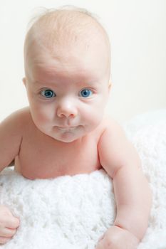 A cute newborn baby boy on a white blanket.