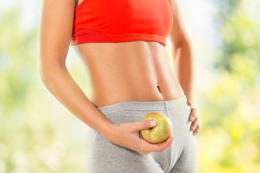 Close-up of a perfect woman body. Woman holding apple. Dieting concept.