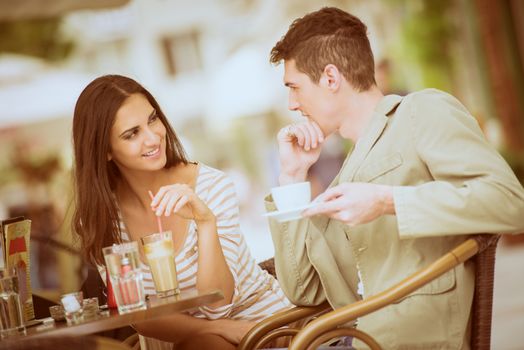 Young couple in garden cafe flirts and enjoys the coffee.