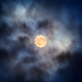 Night view at the full moon through moving blue clouds. Abstract scene