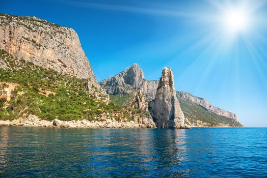 Coast and blue Mediterranean sea and bright sun on the sky in Sardinia, Italy. View from the yacht