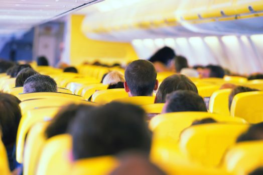 Aisle inside a plane. Interior with passengers on the seats