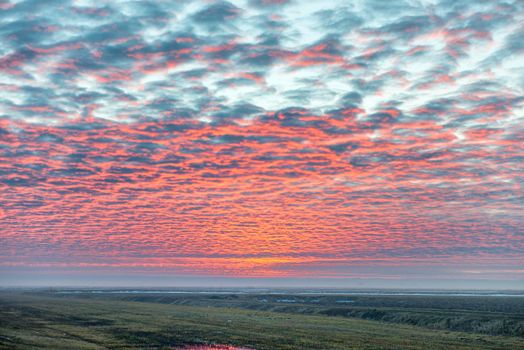 Sunset on the field with red beautiful clouds and sky