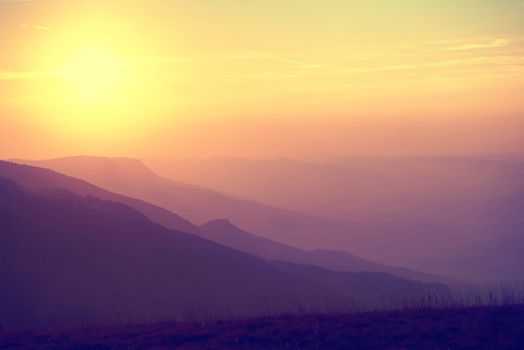 Beautiful sunset at the mountains. Colorful landscape with sun and orange sky. Colorized like instagram