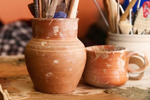 Handmade old clay pots with pencils and other stuff on the table