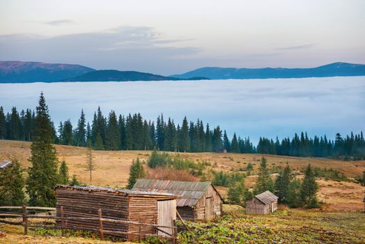 Old house in front of beautiful nature with clouds ocean, field of grass and mountains