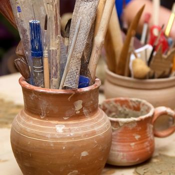 Handmade old clay pots with pencils and other stuff on the table