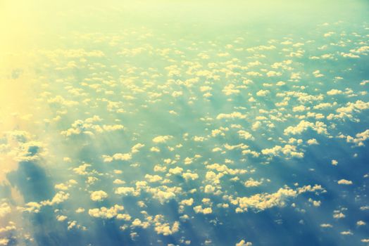 View from a plane to sunset on the sky with sunrays. Fluffy clouds background