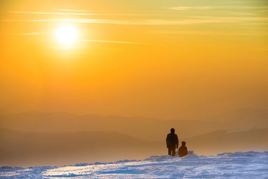 People looking at sunset in winter mountains covered with snow