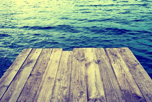 Blue water with empty wooden platform. Natural background, instagram like filter