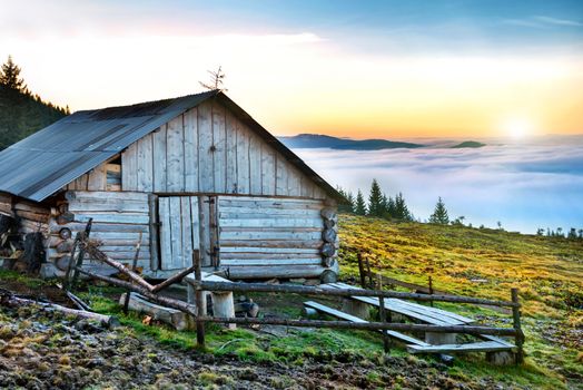 Old house in front of beautiful nature with clouds ocean, field of grass and mountains