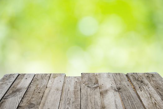 Empty wooden deck table with foliage bokeh background