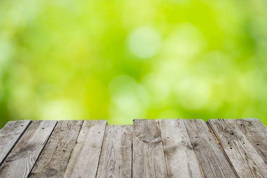 Empty wooden deck table with foliage bokeh background