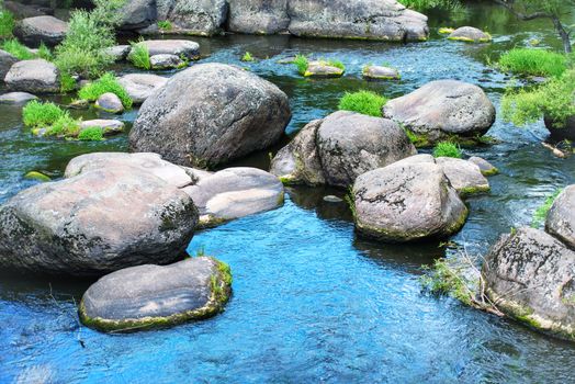 Landscape with stones on the river. Blue sky reflected in the water
