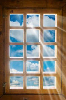 Wooden window with sunbeams shining from beautiful view to blue sky and clouds