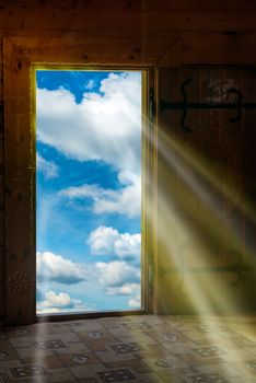 Sun light shining through wooden door from new world with blue sky and clouds
