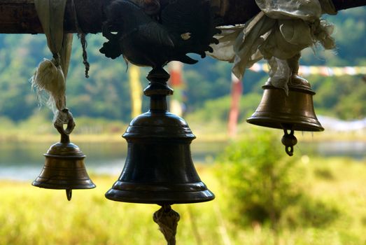 Old bronze bells in indian temple in front of shining green lawn