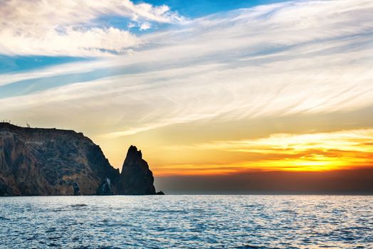 Sea landscape with sunset over rocks and dramatic sky