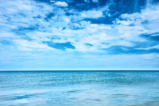 Blue clear sea and sky with white clouds