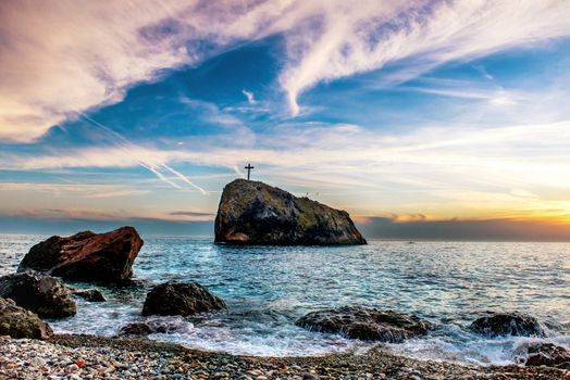 Landscape with sunset on the blue sea beach, rocks and dramatic sky.