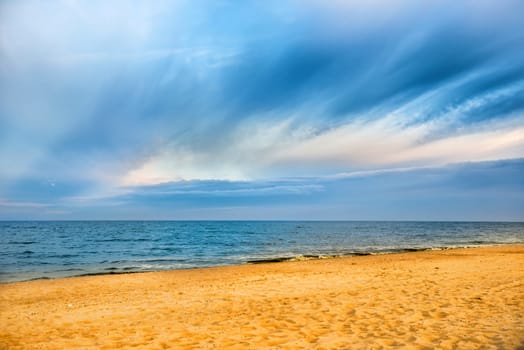 Tropical beach with yellow sand and blue sea with waves, white clouds on background