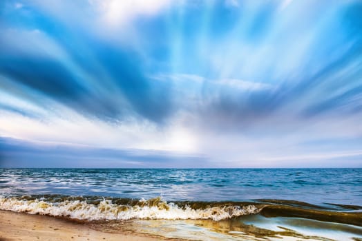 Tropical beach and blue sea with waves, white clouds on background