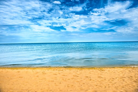 Beautiful summer sea abstract background. Golden sand beach with blue ocean and cloudscape and sunset