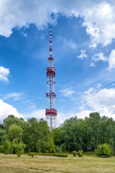 TV tower in the green park over blue sky with clouds