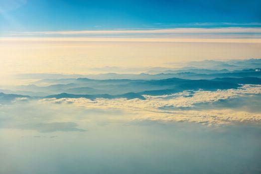 View from a plane to sunset on the sky with sunrays. Fluffy clouds background